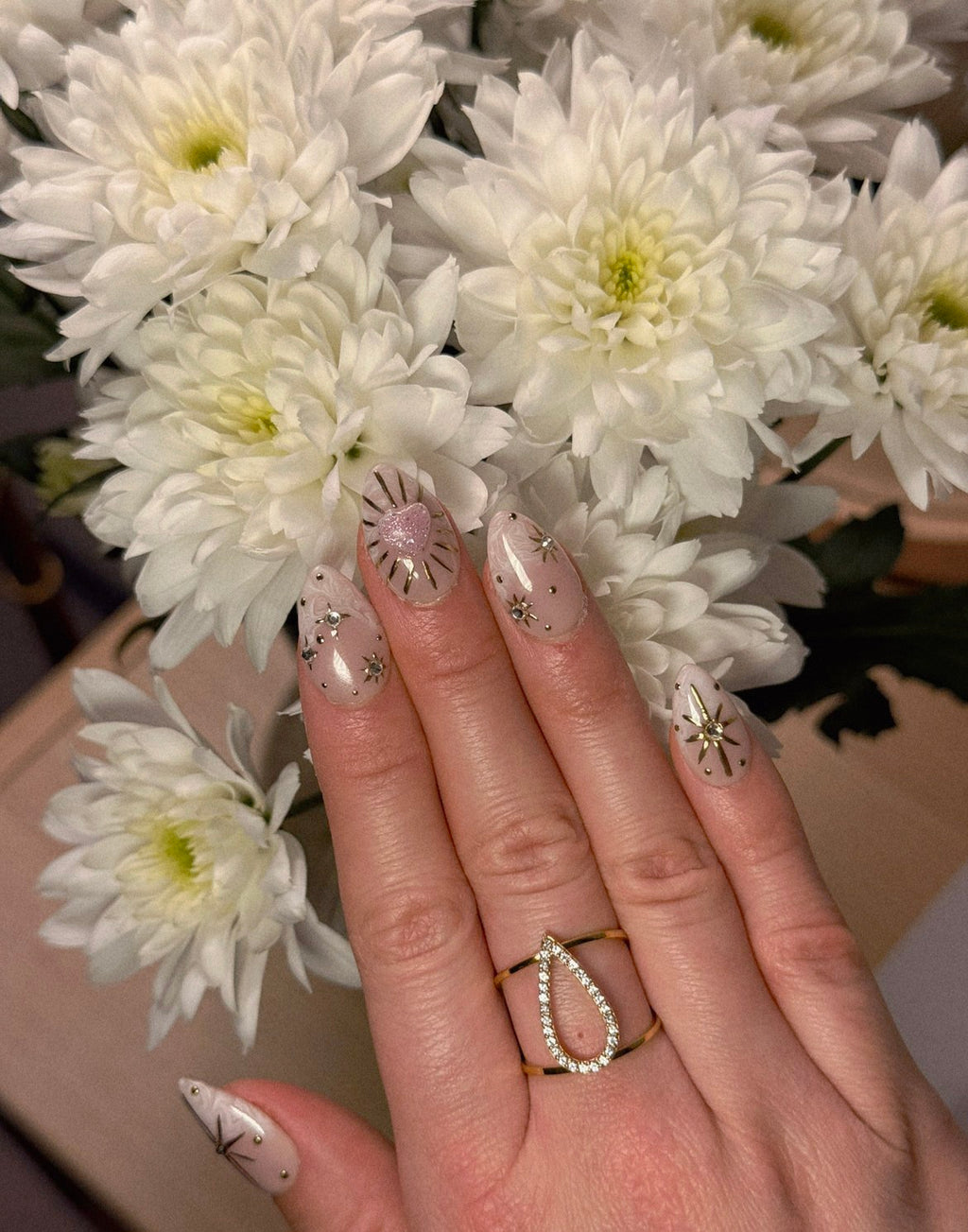 Bague large dorée ajustable et ajourée avec un motif central en forme de goutte évidée pavée de strass brillants.