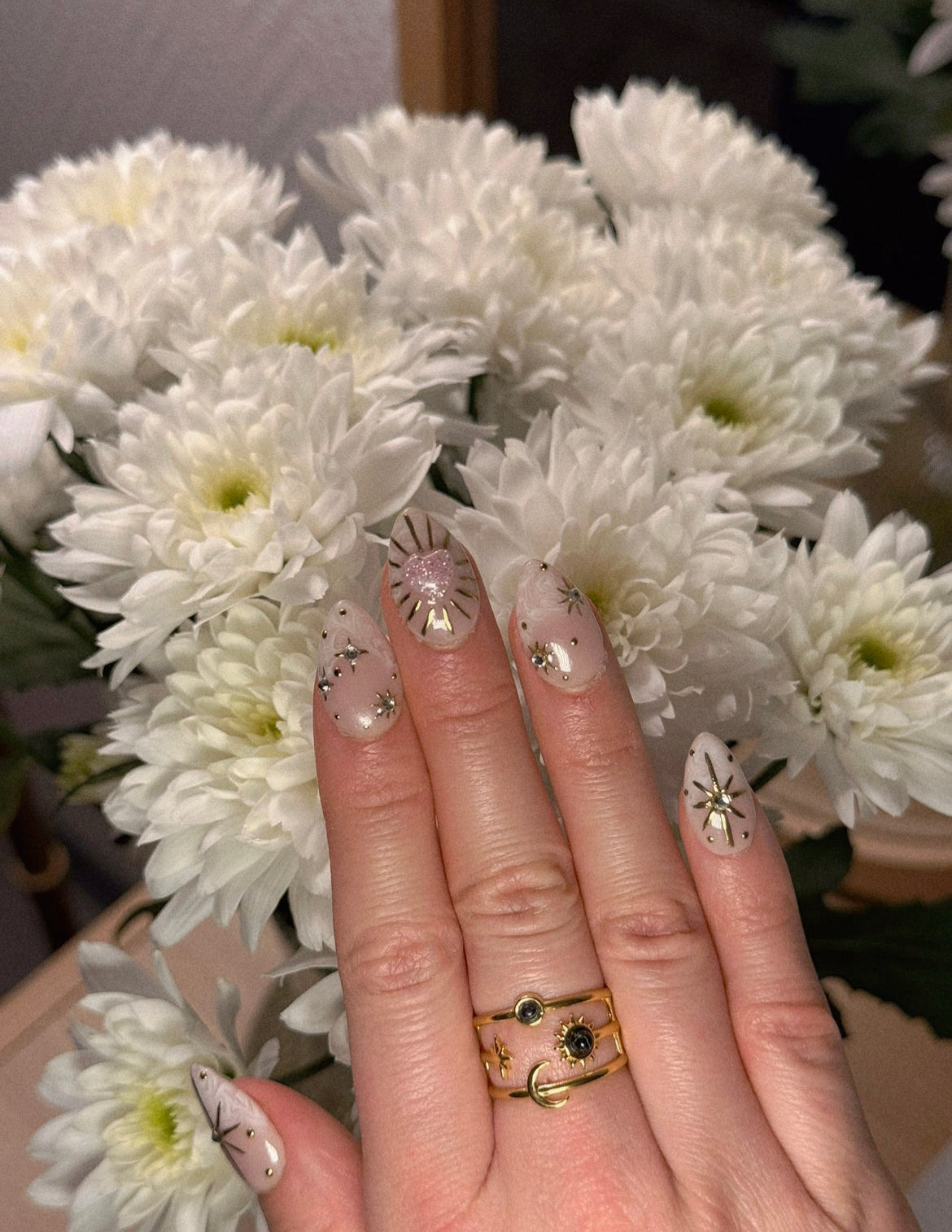 Bague large dorée ajustable et ajourée avec motifs lune, soleil et étoile, sertie de deux pierres rondes noires.
