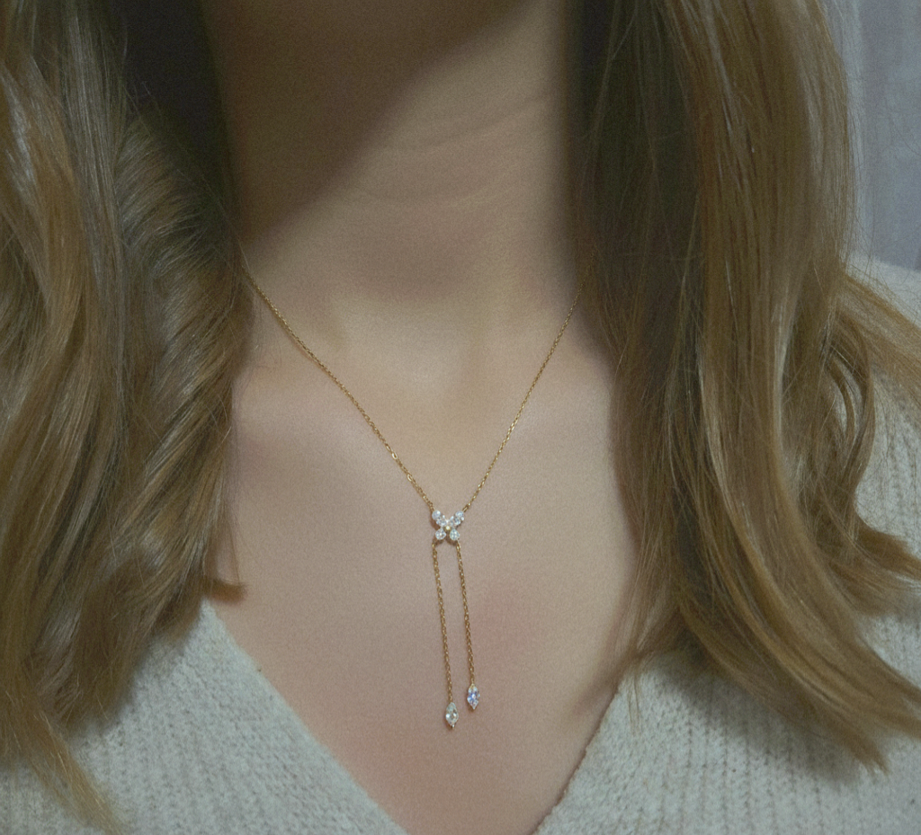 Collier cravate doré avec pendentif papillon en strass et deux fines chaînettes pendantes terminées par des cristaux en forme de goutte.