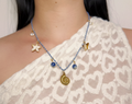 Collier en cordon tressé bleu et blanc avec pendentif coquillage doré, perles bleues et breloque étoile de mer.